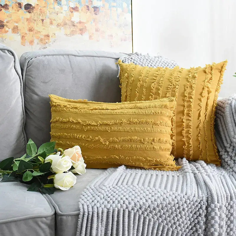 Two mustard-yellow tassel striped pillow covers with fringed texture on a gray sofa for boho home decor