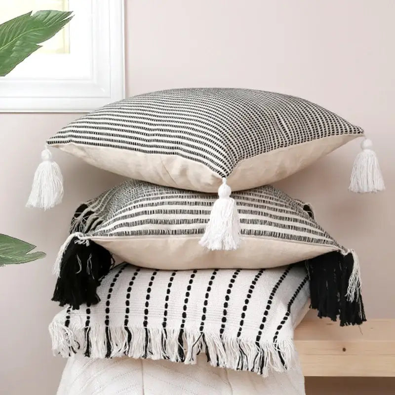 Stack of three black and white boho jacquard flower pillow cases with tassels for living room decor by decorbites