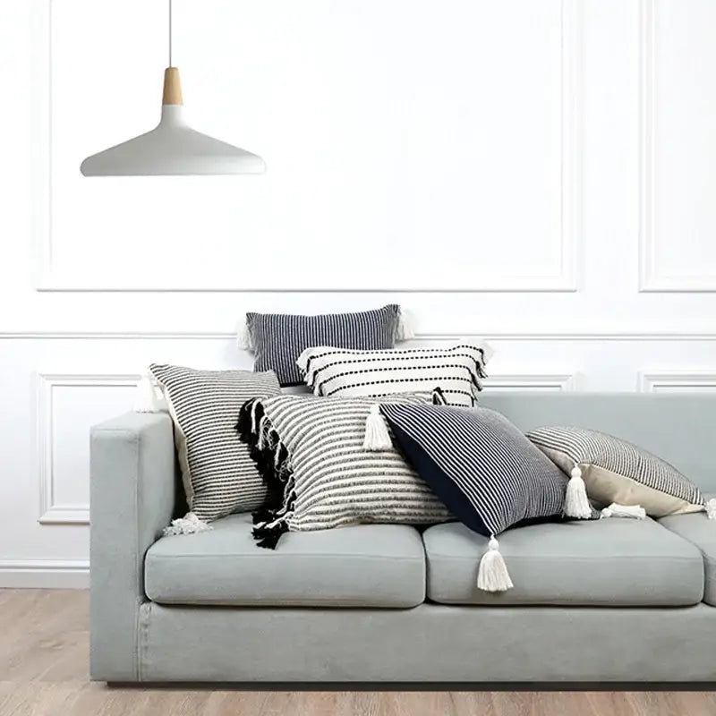 Gray upholstered sofa with multiple striped tassel throw pillows featuring black white and navy boho jacquard flower pillow case decorbites
