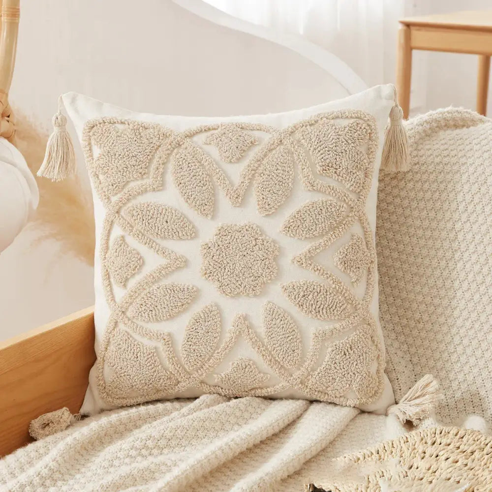 Cream-colored cushion cover with textured embroidered leaf pattern and tufted tassel cushion details for living room