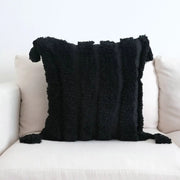 Boho black and white tufted tassel cushion cover featuring a black textured throw pillow with fringed vertical stripes and tassels