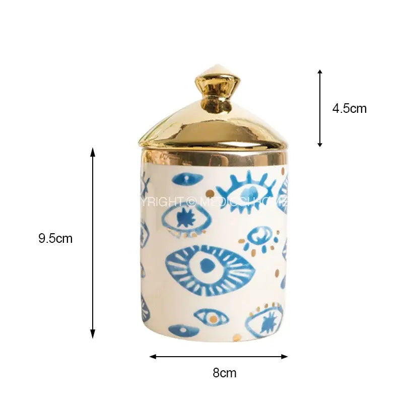 A white ceramic jar with a gold lid featuring blue and gold eye motifs for decorbites bright eyes ceramic dinner decor