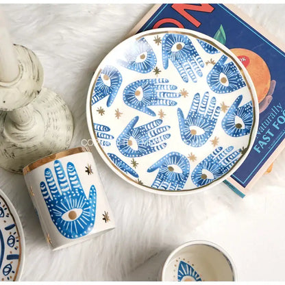 White ceramic eyes ceramic dinner plate with blue hamsa hand designs and gold accents from decorbites bright eyes collection
