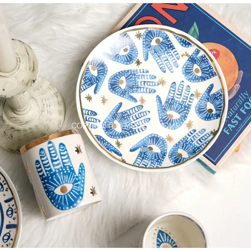 White ceramic eyes ceramic dinner plate with blue hamsa hand designs and gold accents from decorbites bright eyes collection