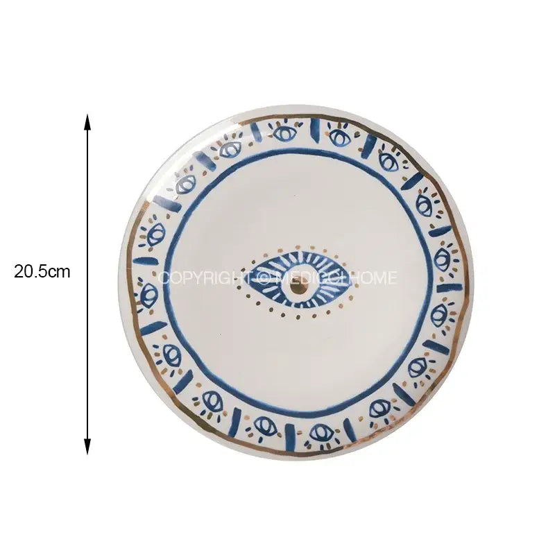 A white boho blue and gold bright eyes ceramic dinner plate with central eye motif and decorative borders for dining room decorbites bright eyes