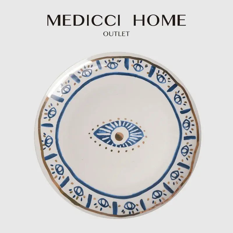 A white ceramic boho bright eyes ceramic dinner plate with blue and gold eye motifs from medicci home decorbites bright eyes