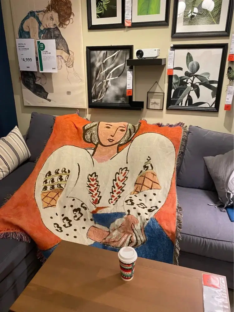 Orange and blue woven boho chic throw blanket with stylized woman design draped over gray sofa decorbites boho chic
