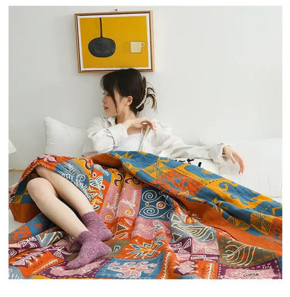 A decorbites boho cotton blanket with bold orange blue and pink geometric patterns draped over a lap for bedroom decor