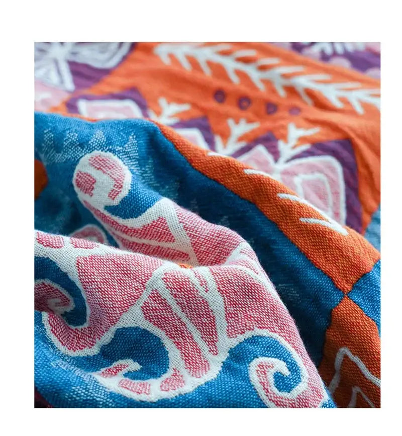 Vibrant decorbites boho cotton blanket featuring bold blue and orange patchwork with intricate pink and white embroidery