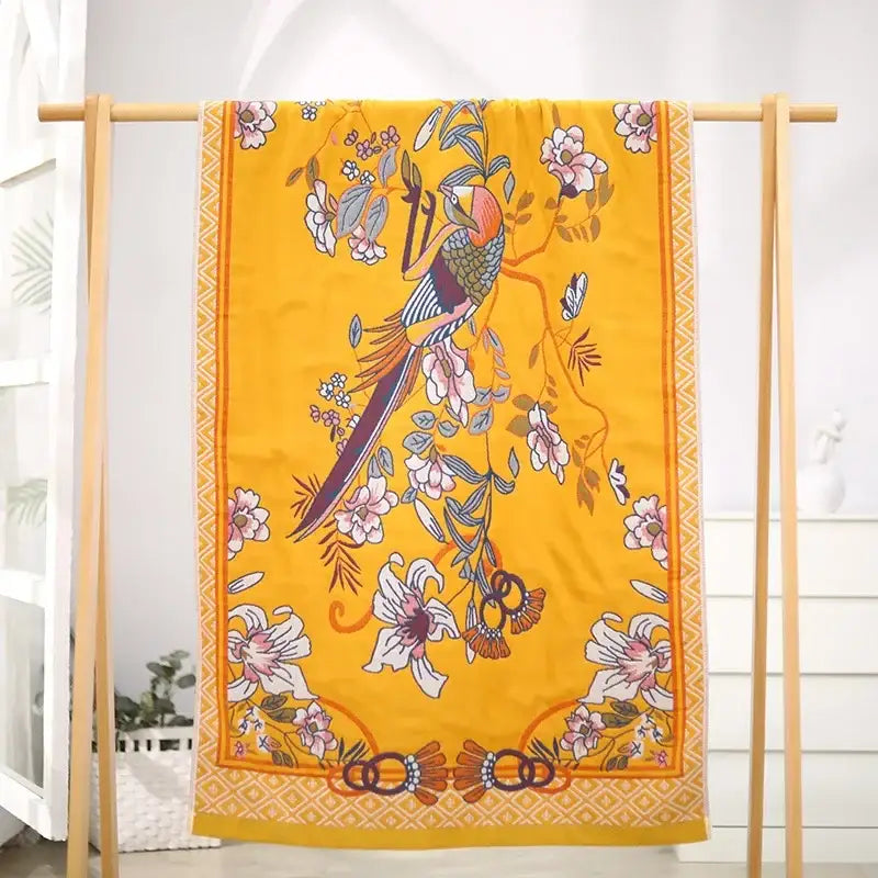 A vibrant yellow silk scarf with a colorful bird and floral design complements decorbites boho cotton gauze bath towel wrap