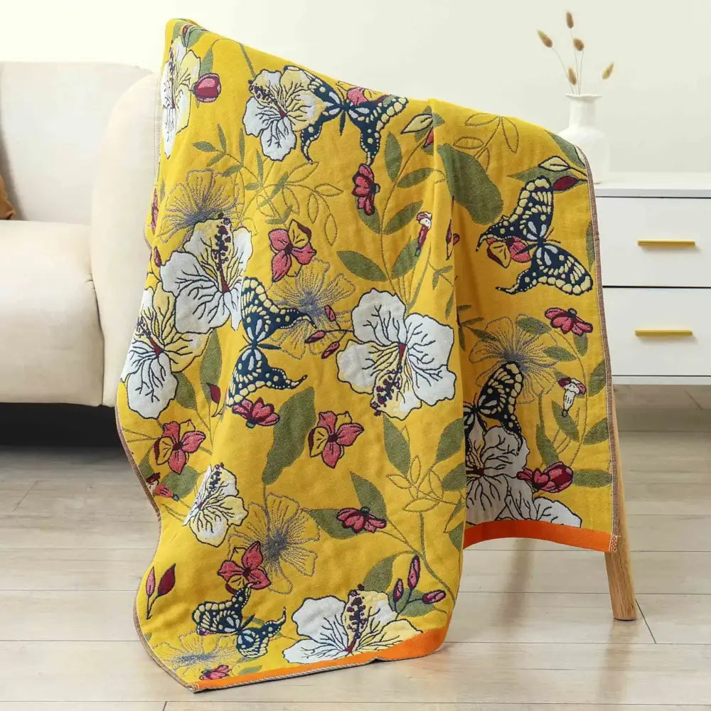 A vibrant yellow decorbites boho cotton gauze bath towel featuring butterfly and floral patterns for stylish bathroom wrap