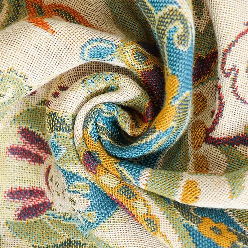 A cream-colored decorbites boho cotton gauze bath towel with a vibrant blue yellow and maroon swirling pattern