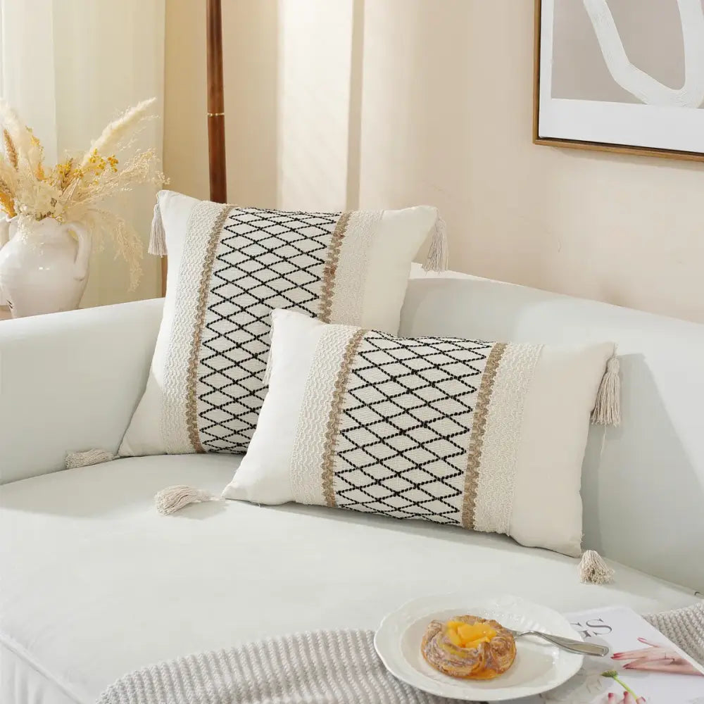 Cream-colored woven cushion cover with black diamond embroidery and beige tassels for boho living room decor
