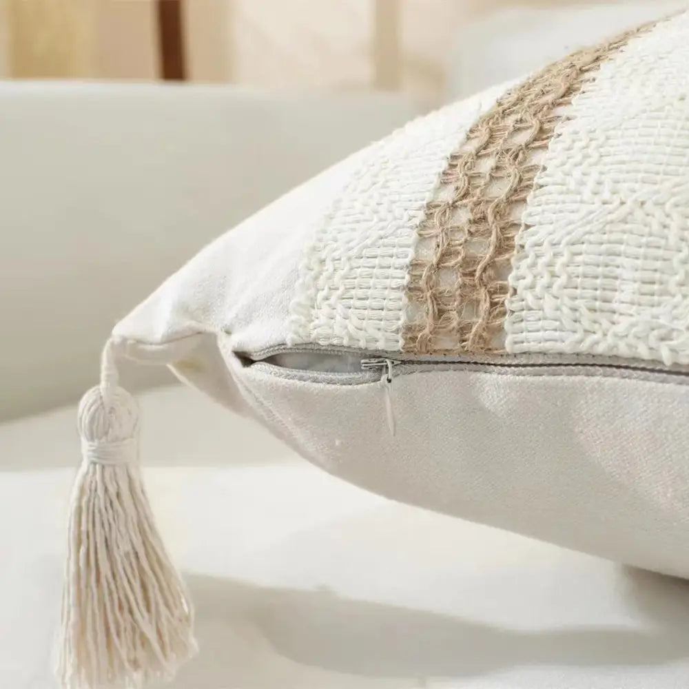 Boho cream woven cushion cover with white and beige textured stripes, tasseled corner, and silver zipper closure