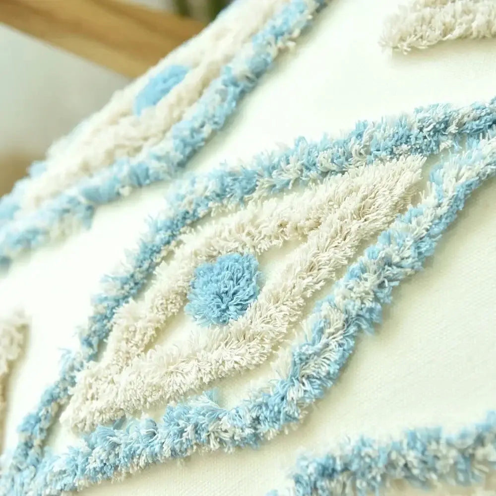 A cream cushion cover with textured embroidered eye in light blue and white yarn for decorbites boho blue diamond decor