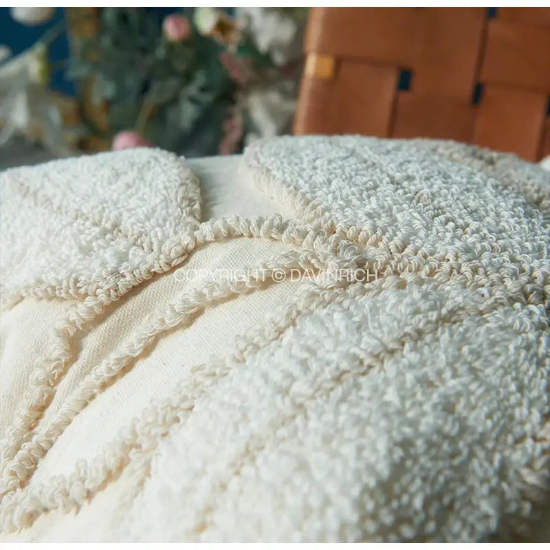 Cream-colored textured moroccan-style pouf with hand-knotted woolen surface and intricate decorbites boho leaf geometry tufted cushion cover