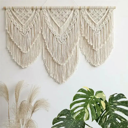 Cream-colored macrame wall hanging tapestry with intricate geometric patterns and long flowing fringe for bedroom decor