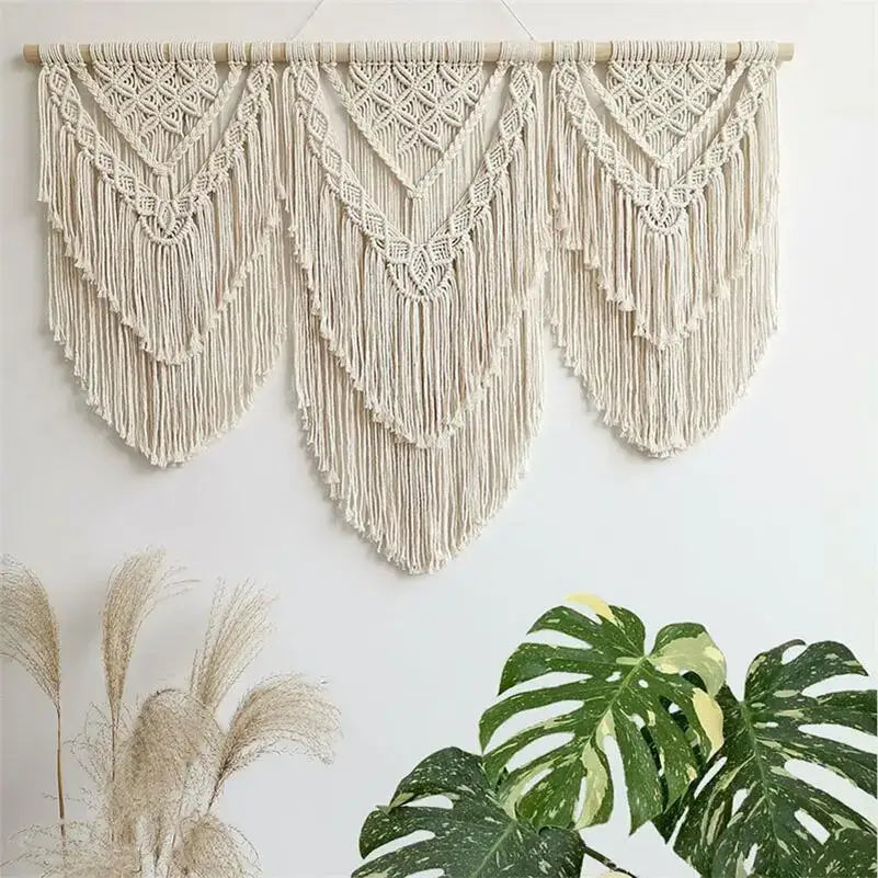 Cream-colored macrame wall hanging tapestry with intricate geometric patterns and long flowing fringe for bedroom decor