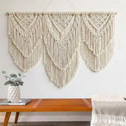 Cream-colored macrame wall hanging tapestry featuring intricate geometric patterns and long fringe for boho decor