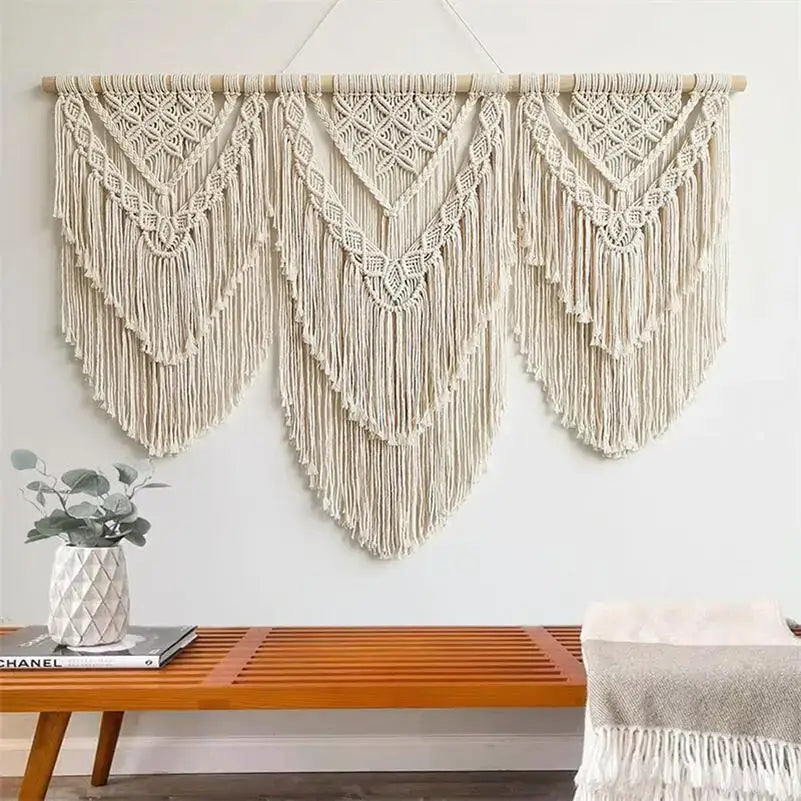 Cream-colored macrame wall hanging tapestry featuring intricate geometric patterns and long fringe for boho decor