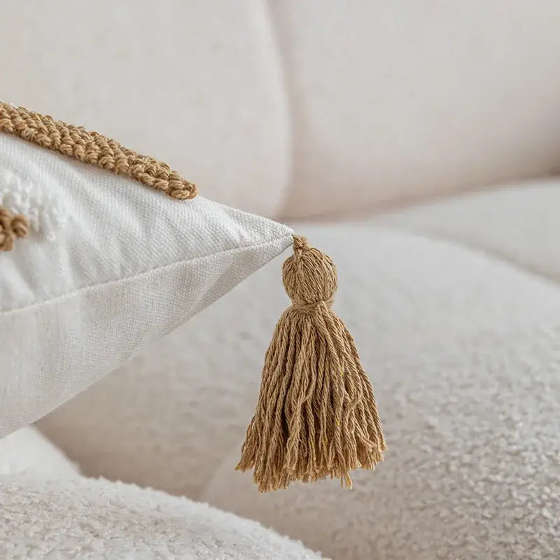 Beige woven tassel detail on a white textured boho cream and tan geometric tufted fringe cushion cover