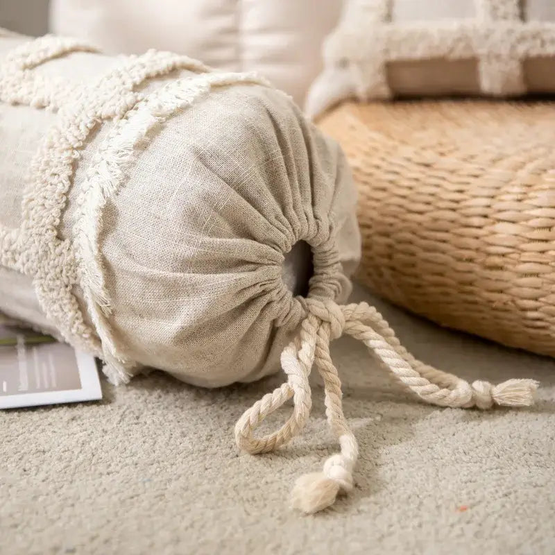 Beige linen cylindrical pillow with frayed tassel trim and drawstring closure in boho cream textured pillow cover set