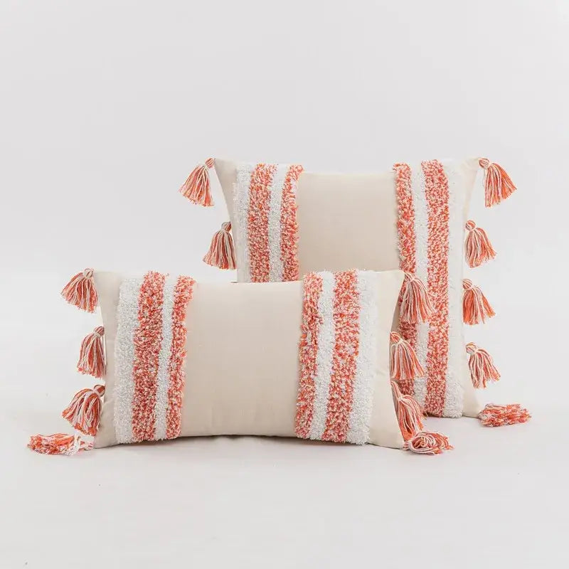 Cream-colored tufted cushion cover with coral and white textured stripes and tassels for living room decor