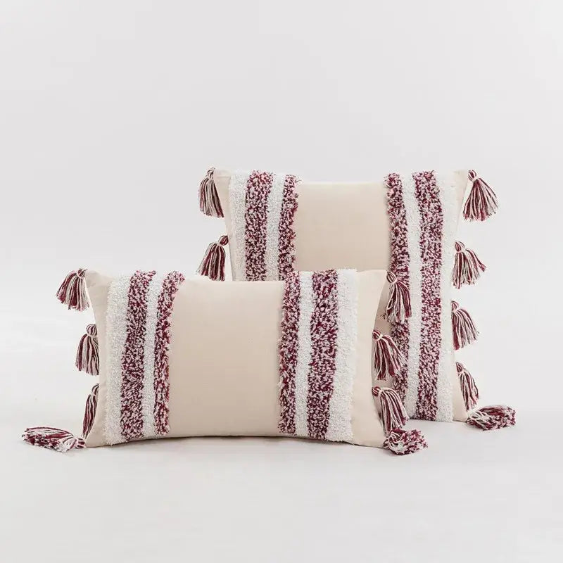 Cream-colored tufted cushion cover with maroon and white textured stripes and tassels for living room decor