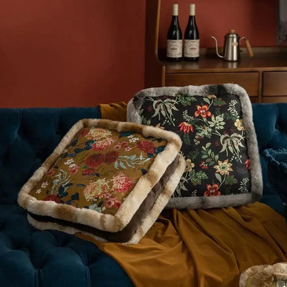 Two boho dark floral square seat cushions with gray faux fur trim resting on a velvet dining room sofa