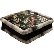 Square-shaped cushion with a dark floral patterned fabric top, trimmed in soft gray faux fur along its edges and base.