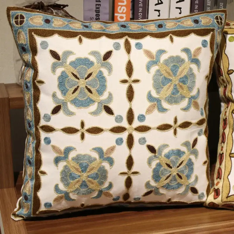 Square decorative pillow with blue and brown embroidered floral patterns on cream fabric for ethnic flower elephant decorbites use