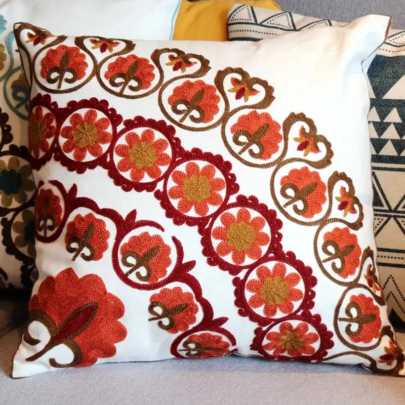 White pillow with intricate red and orange floral embroidery and swirling brown patterns for decorbites ethnic flower decor