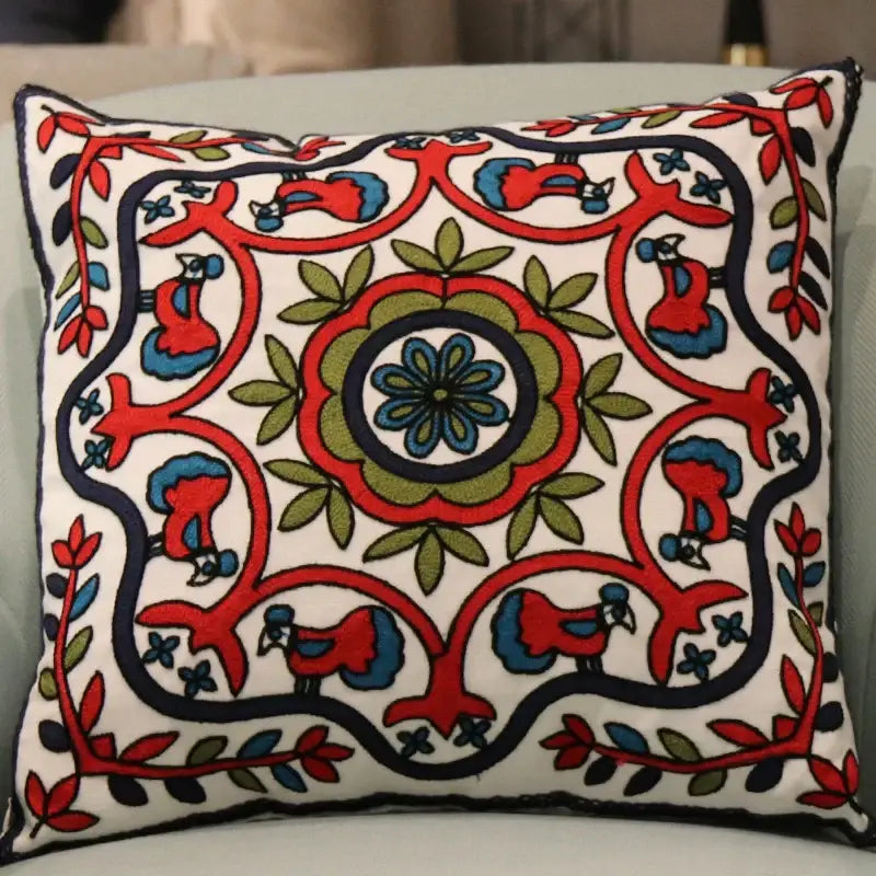 A white square flower elephant pillowcase with intricate red blue and green embroidered birds and floral decorbites ethnic flower motifs