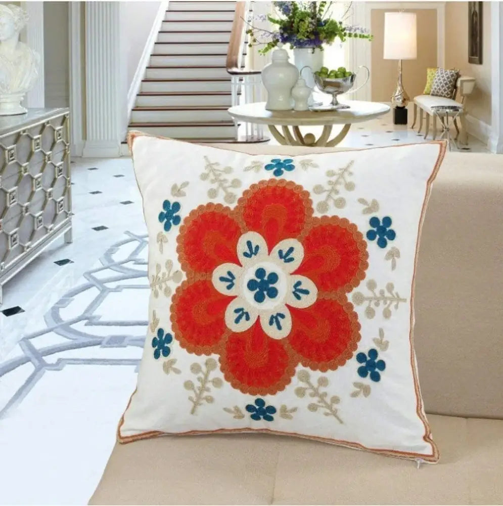 White cushion pillow cover with vibrant orange and blue embroidered boho farmhouse floral design for living room decorbites