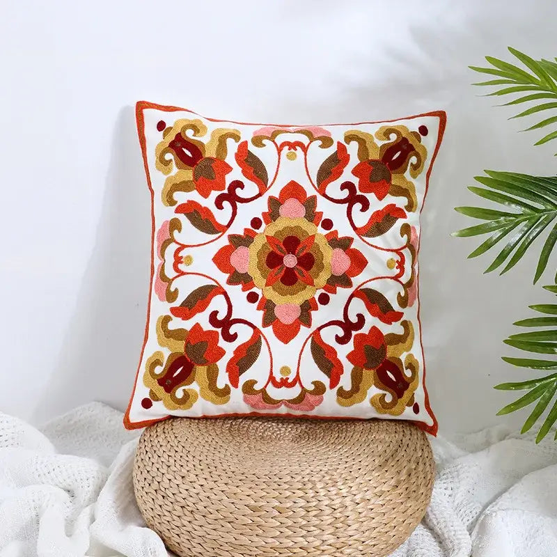 A square white pillow cover with intricate boho farmhouse floral embroidery in reds pinks golds and browns decorbites boho farmhouse