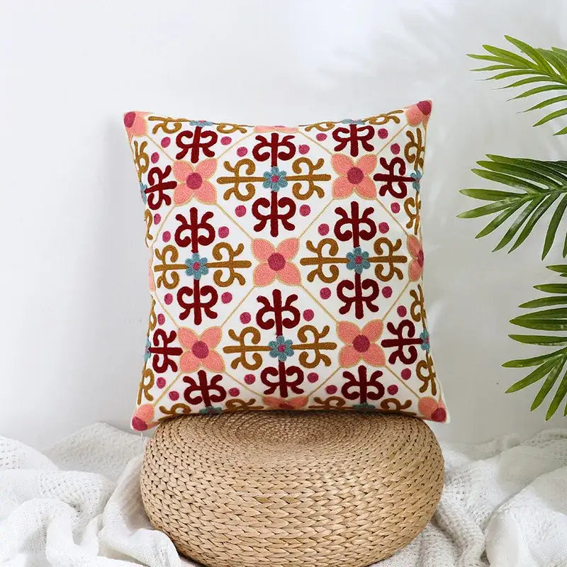 A square boho farmhouse floral cream embroidered pillow cover with vibrant pink red flowers and gold teal details by decorbites