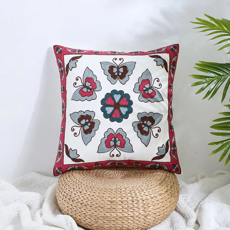 Square embroidered pillow cover with boho farmhouse floral design in cream featuring colorful butterfly and floral patterns by decorbites
