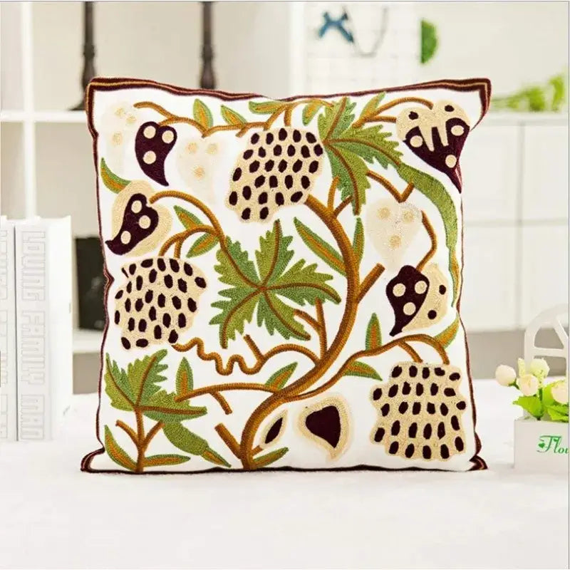 White cushion pillow covers featuring intricate boho farmhouse floral embroidery with green leaves and dark purple berries