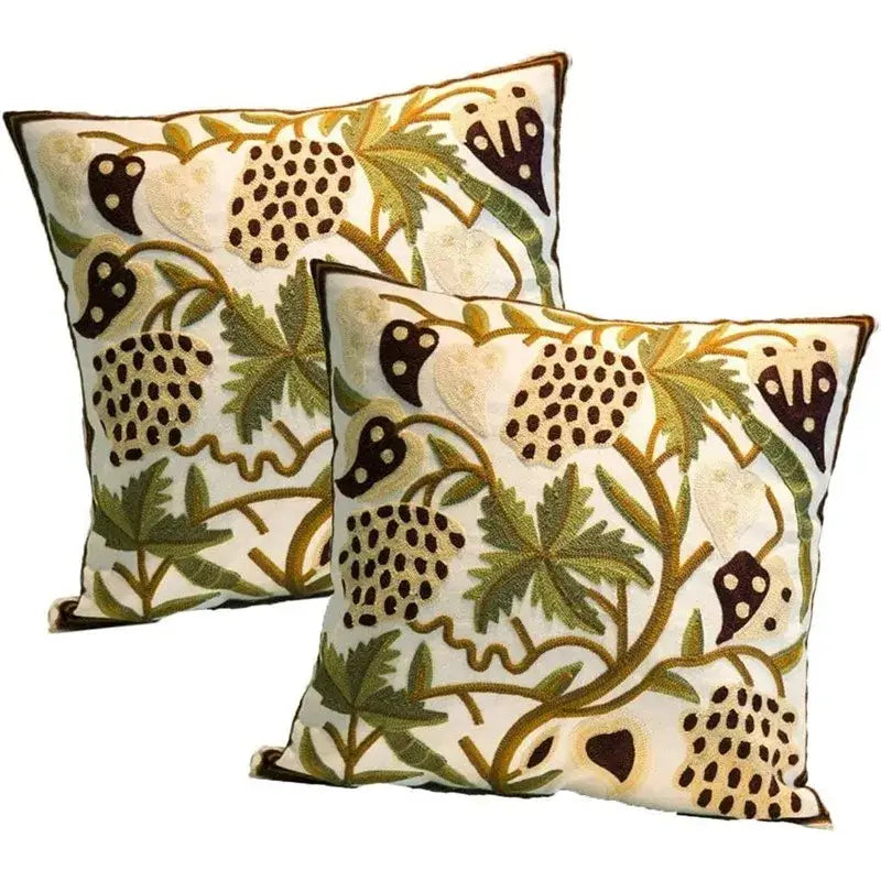 Cream-colored pillow covers with intricate olive green mustard yellow and dark brown embroidered boho farmhouse floral patterns