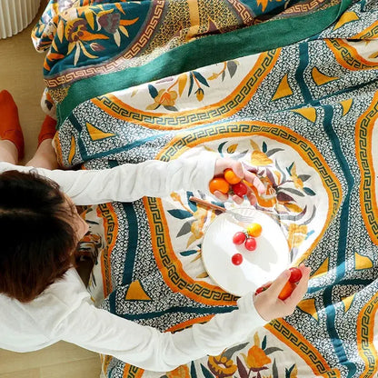 A person seated on a patterned boho floral cotton gauze leisure blanket in teal orange and yellow decorbites cotton gauze