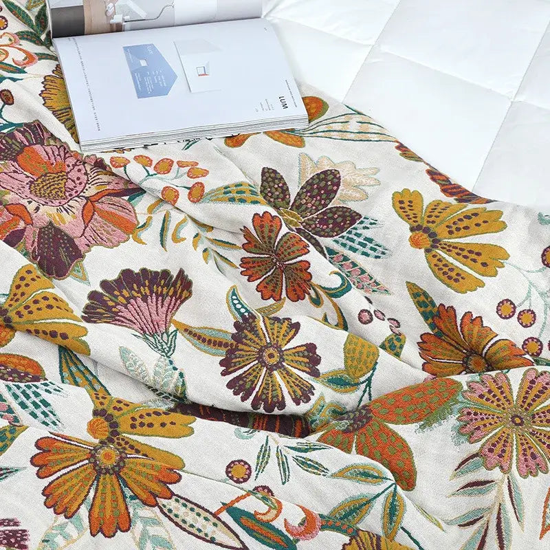 A cream cotton bedspread with vibrant orange pink and green floral embroidery perfect for a boho cotton bedspread