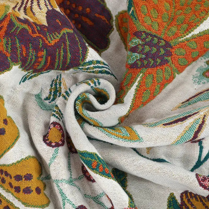 A soft off-white boho cotton bedspread with vibrant embroidered butterflies in orange purple green and yellow
