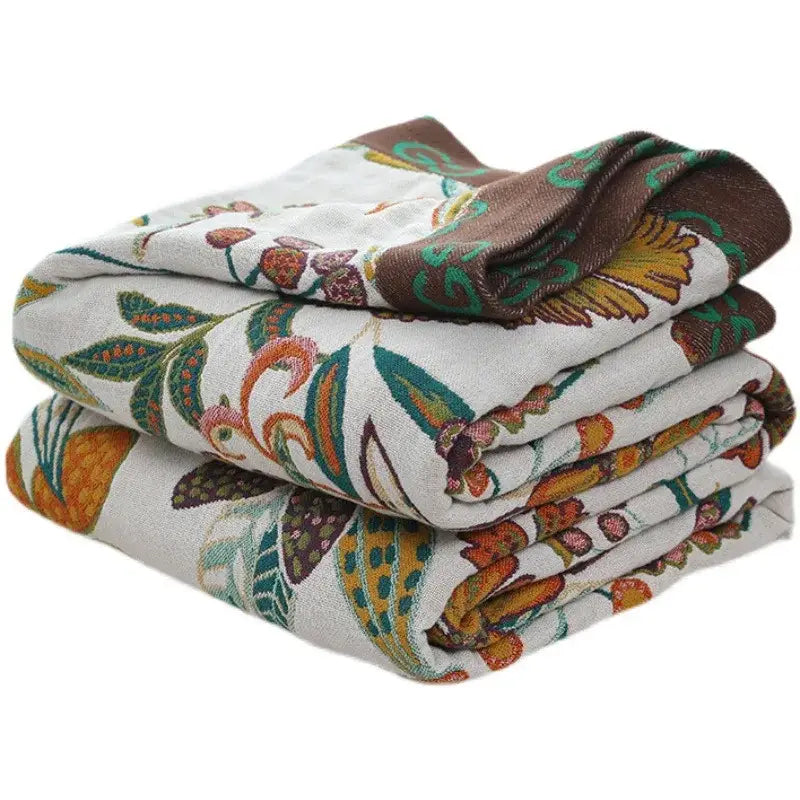 Stacked embroidered towels with botanical pattern in earthy tones complementing boho cotton bedspread for bedroom