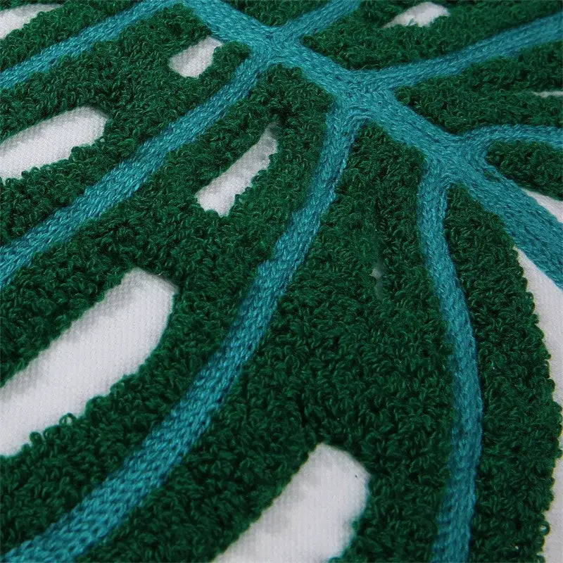 Boho floral embroidered cushion cover featuring textured green and teal monstera leaf pattern on white fabric by decorbites