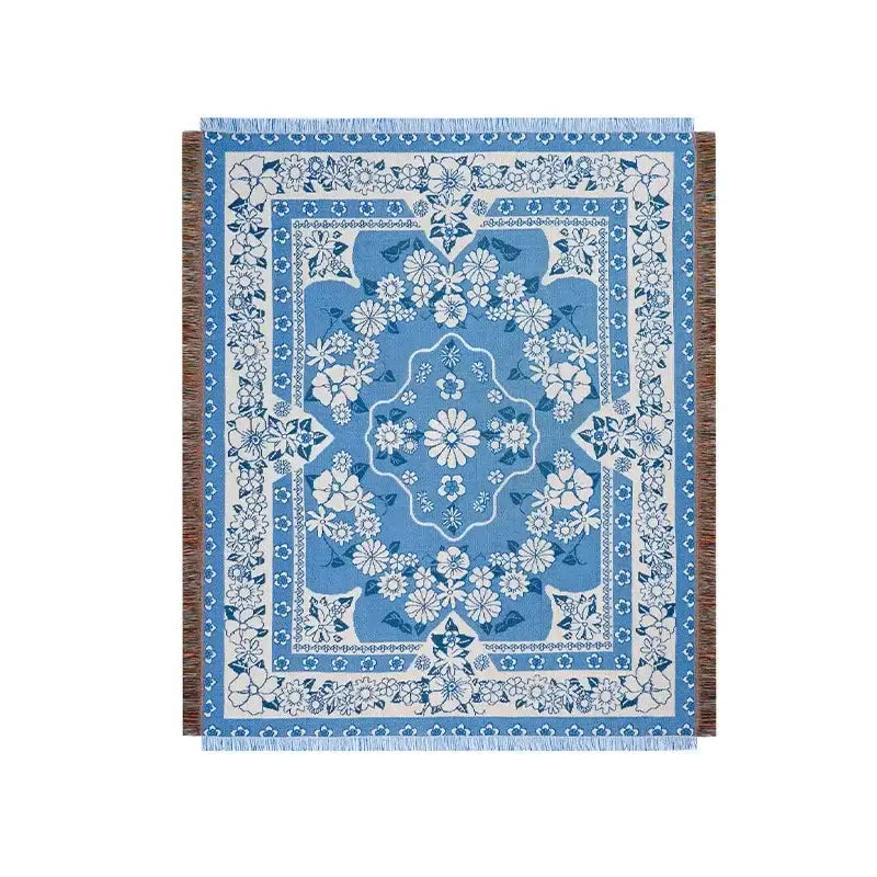 Blue and white floral patterned throw blanket with fringed edges.
