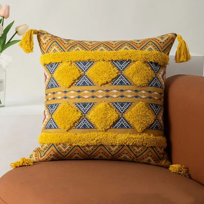 Vibrant mustard-yellow and navy geometric-patterned throw pillow with fluffy tassels.