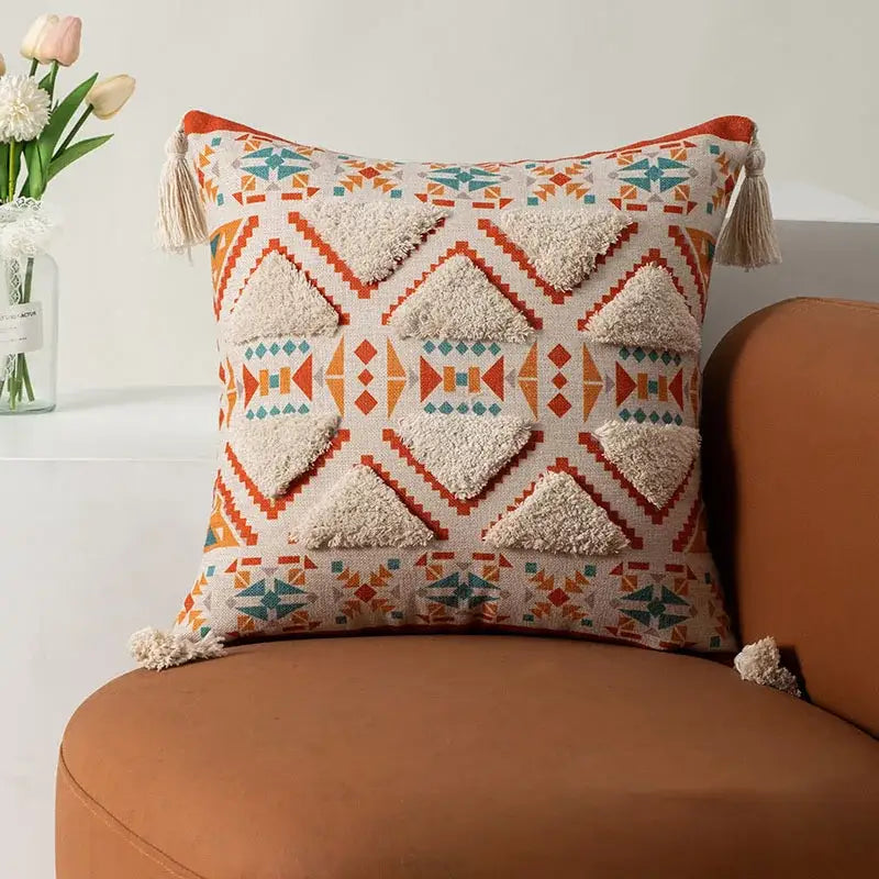 A cream-colored boho fringe pillow cover with orange and teal geometric appliqués and tassels for decorbites boho fringe decor