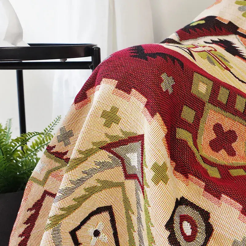 A cozy throw blanket with a vibrant red beige green and black geometric pattern for boho geo ethnic decorbites style