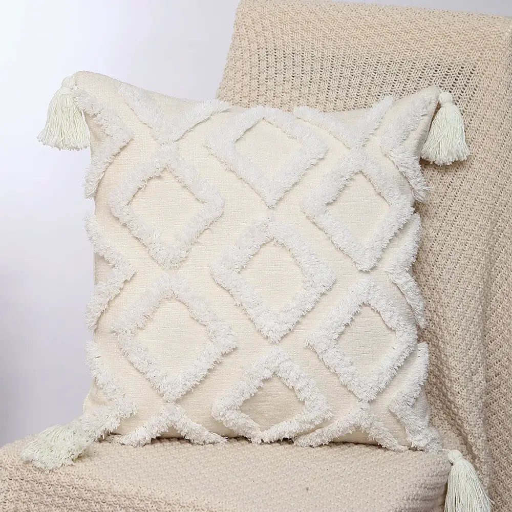 Cream-colored boho geometric chenille embroidered pillow cover with textured diamond pattern and frayed tassels for decorbites