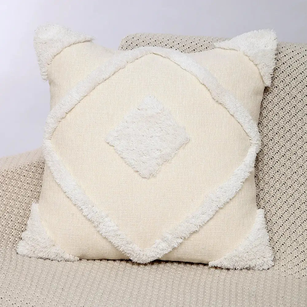 Cream-colored square pillow cover with frayed white trim and central textured diamond patch in decorbites geometric chenille style